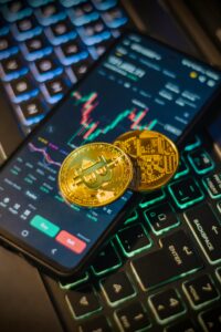 Cryptocurrency trading interface on a mobile with Bitcoin coins on a laptop keyboard.